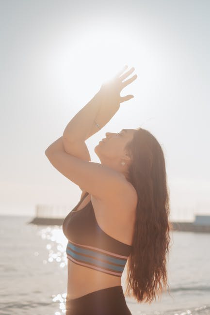 Person in a gentle yoga pose on a serene beach at sunrise